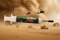 One third ounce syringe with high temperature Gun Werkz Extreme grease on a desert storm background with helicopters in the air and tanks on the ground with explosions in the distance
